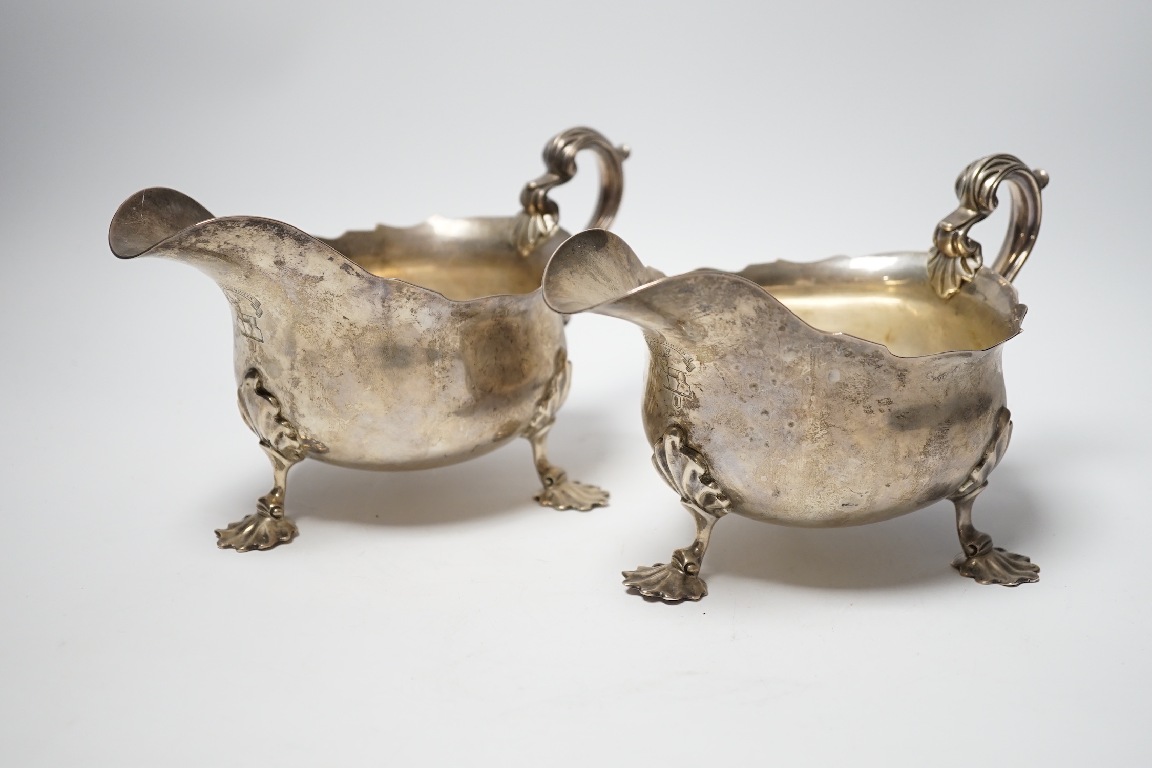 A pair of Edwardian silver sauce boats with shell knees, on three fluted feet, Carrington & Co, London, 1902, length 20.8cm, 33.9oz.